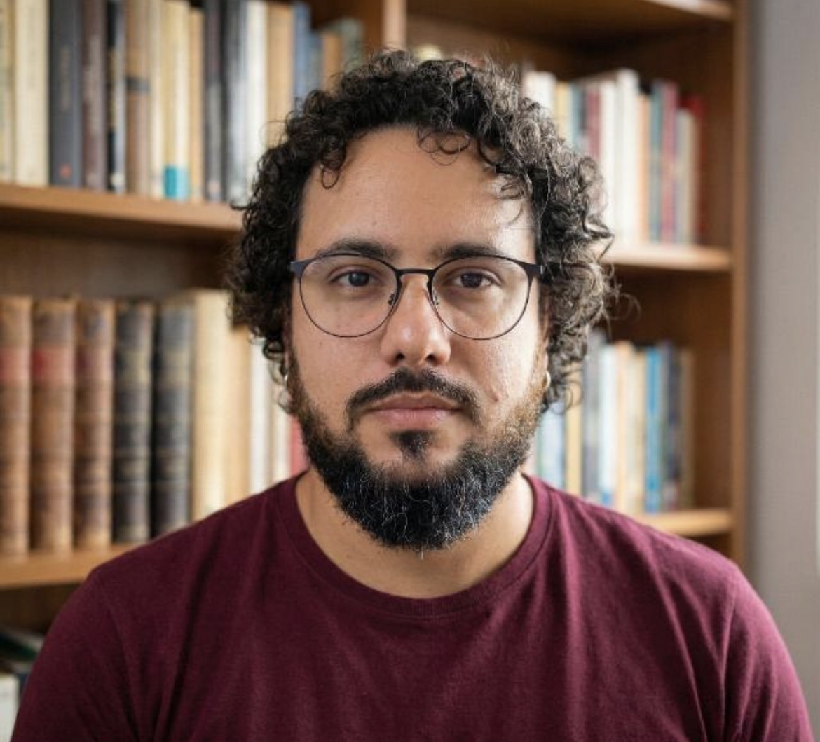 Retrato de Cristian Arão diante de uma estante de livros